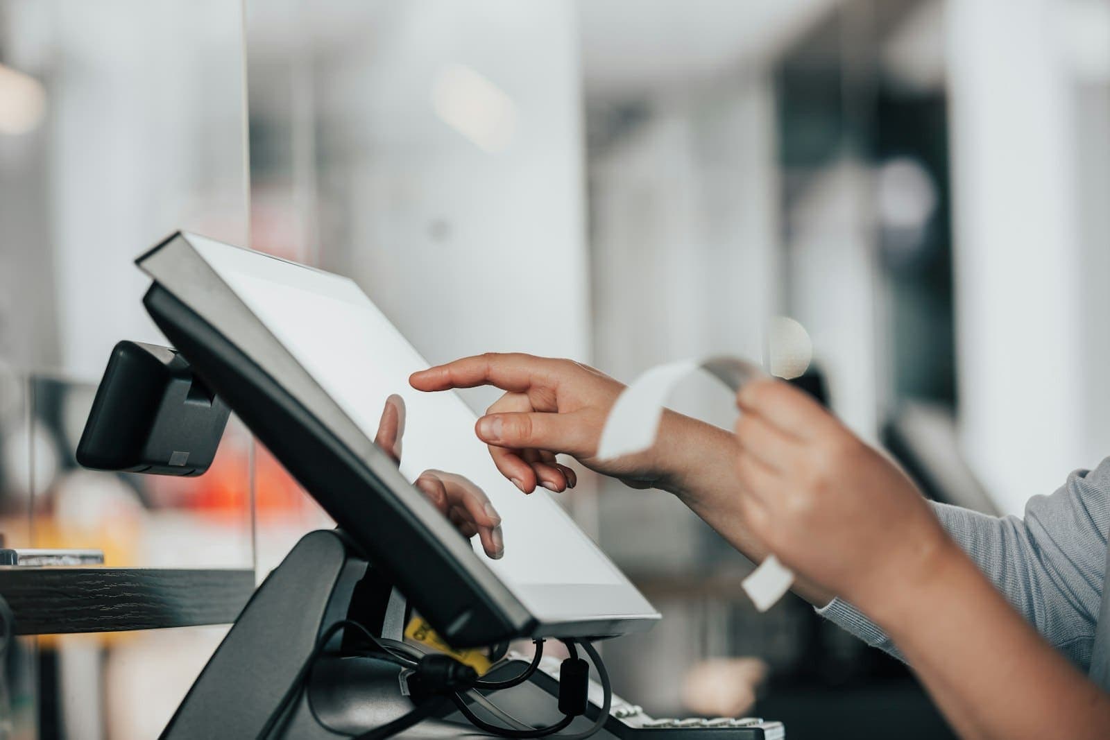 A member of staff ringing up a sale on a touchscreen till and handing over a receipt